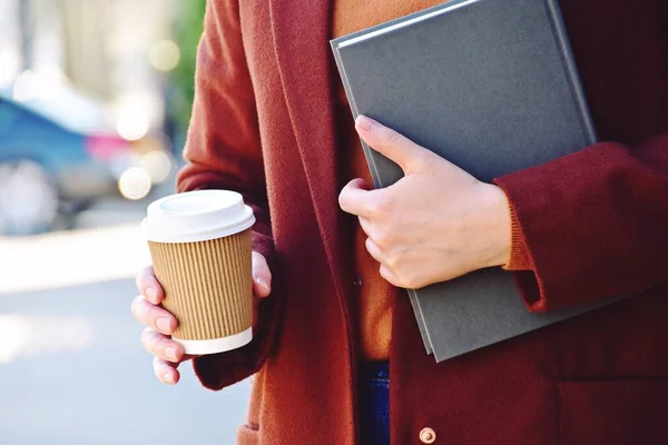 Elinde bir kitapla görülen paket kahve. Güneşli bir günde kahve.