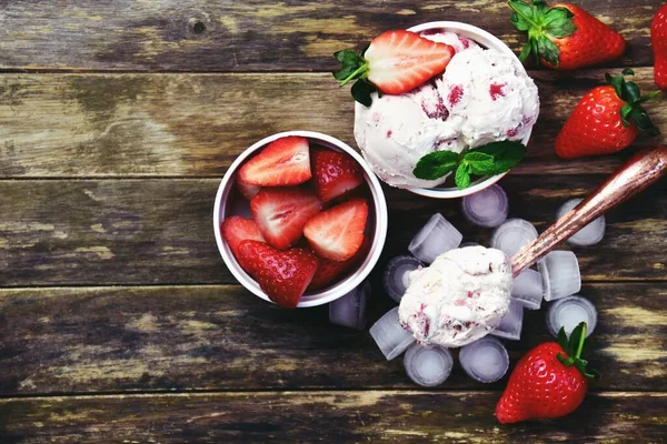 Ahşap arka planda iki kase çilekli dondurma. Boşluğu ve üst görünüm fotoğrafını kopyala