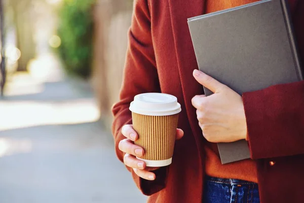 Elinde bir kitapla görülen paket kahve. Güneşli bir günde kahve.