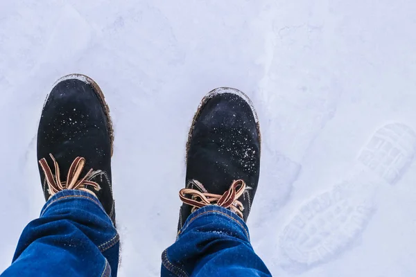 Legs in jeans and boots in the snow.