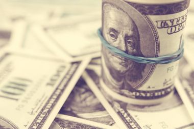 Yüz dolarlık banknotlar mavi lastik bant konumu olan rulo dolar faturaları arka plan üzerinde. Tonda