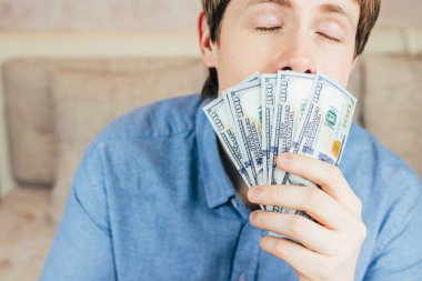 genç adam yeni 100 dolar faturaları kokusu nefes alır.