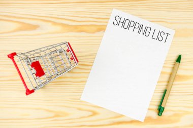Alışveriş listesi mockup, alışveriş sepeti, kalem, ahşap arka plan kompozisyon üzerinde. Alışveriş kavramı