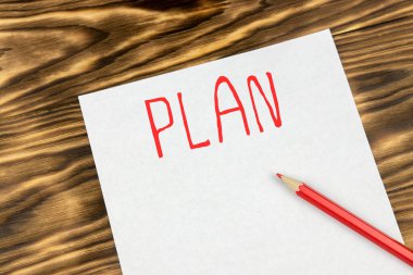 Ahşap arka plan üzerinde kırmızı kalem ile metin ile beyaz kağıt yaprağının. planlama kavramı
