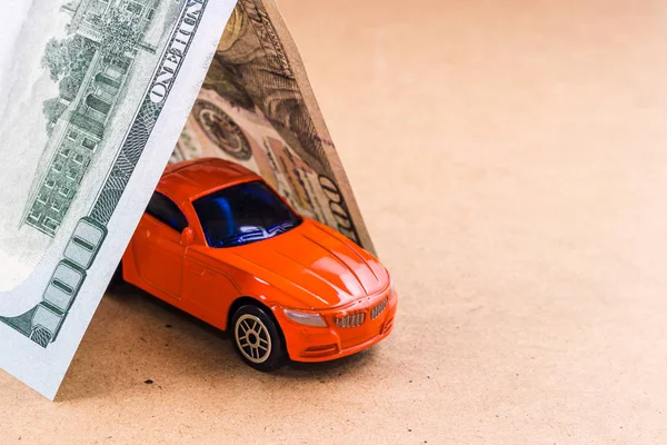クローズ アップ百ドル法案屋根は 茶色の背景に赤い車のおもちゃをカバーしています 車保険の概念 — ストック写真