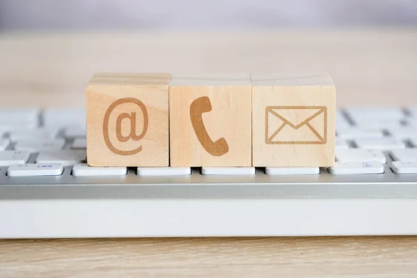 Houten kubus met de beeldsymbolen van e-mail, telefoon en post. Contactconcept voor communicatie. — Stockfoto