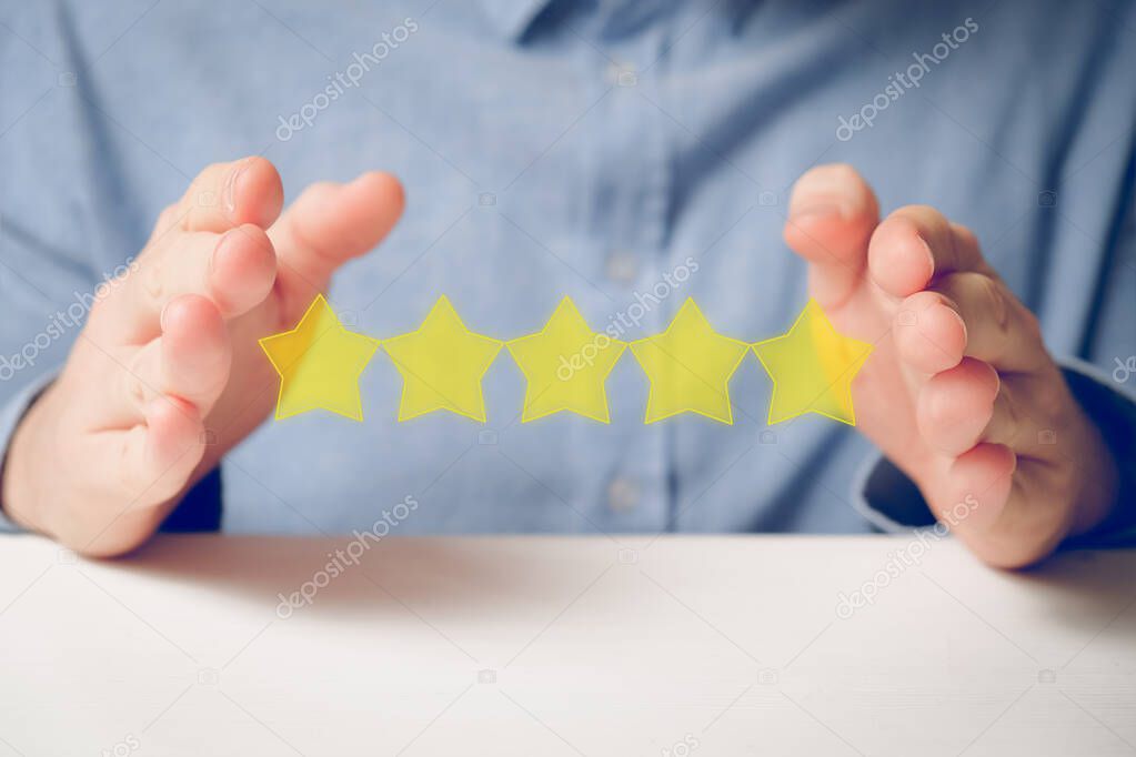 A man in a shirt abstractly shows the rating with his hands five stars. Best score