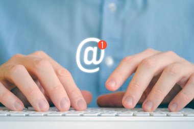 Klavyenin önünde tişörtlü bir adam. Yeni iletiye sahip soyut e- posta simgesi.