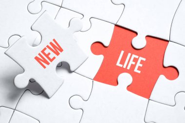 Yeni bir hayat kavramı. Üzerinde yazı olan bulmacanın bir parçası kırmızı arka planda bir adamın parmaklarını bir diğerinin yanında tutuyor..