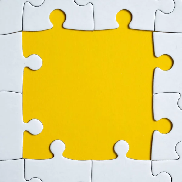 Imagem quadrada de um quebra-cabeça branco sobre um fundo amarelo. Fecha. Depósito plano . — Fotografia de Stock