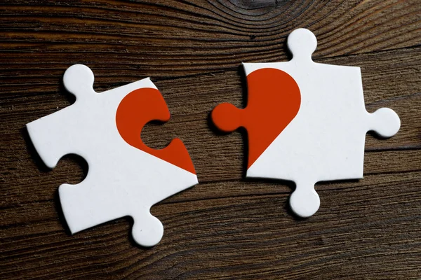 O conceito de separação e não de amor mútuo. Peças de um quebra-cabeça branco em um fundo de madeira . — Fotografia de Stock