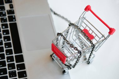 Tramvayın yanındaki masada gri bir dizüstü bilgisayar ve süpermarketten sarmalanmış bir zincir. Alışveriş kolik hastalık konsepti.