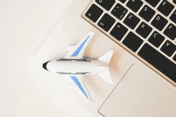 모델 비행기는 노트북 위에 서 있습니다. 온라인 비행 스케줄 재검토 컨셉. 맨 위 사진. — 스톡 사진