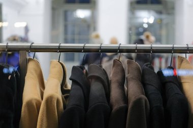 Dükkanın camında farklı paltolar olan askılar..