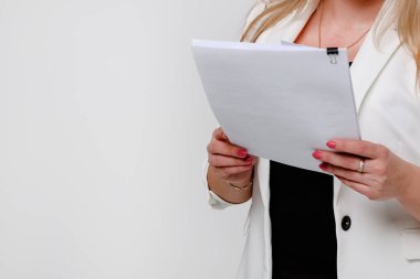 Beyaz arkaplanlı ceketli bir kız bir yığın evrak ve belgeyi silkeliyor..