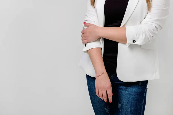 Een meisje in een jasje in een geklemde houding op een witte achtergrond. Begrip onzekerheid. — Stockfoto