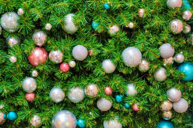 The wall is decorated with green branches with Christmas decorations in the form of balls.