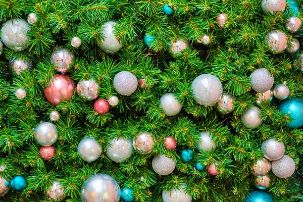 De muur is versierd met groene takken met kerstversieringen in de vorm van ballen. — Stockfoto