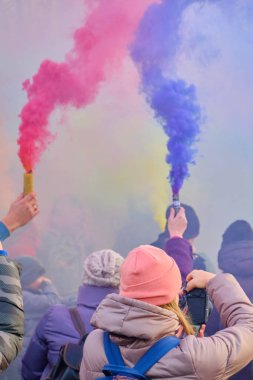 January 05, 2019, St. Petersburg: A crowd of people walk at the festival of colored smoke. Hands hold colored firecracker with smoke.