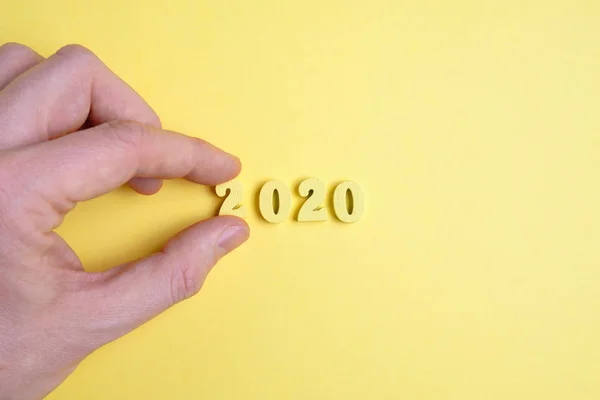 La main tient le numéro deux côte à côte sur fond jaune. Le concept de la nouvelle année 2020 . — Photo