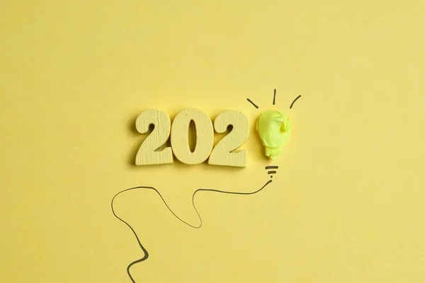 The concept of new ideas. Abstract paper light bulb with 2020 numbers on a yellow background. Top view.