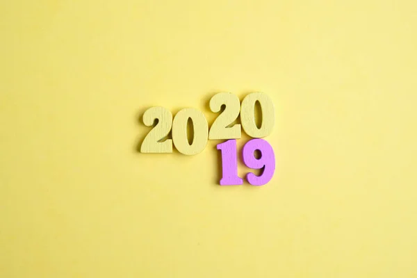 Letras de madeira na forma de números em um fundo amarelo. O conceito de mudança de ano de 2019 para 2020 . — Fotografia de Stock