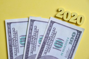 2020 'deki yeni yatırım kavramı. Sarı arka plandaki ahşap figürlerin yanında dolar. Üst görünüm.