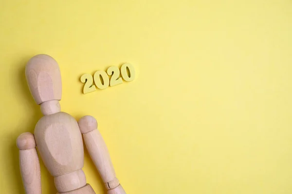 Un mannequin en bois à côté des chiffres 2020. Le concept de l'homme dans la nouvelle année . — Photo