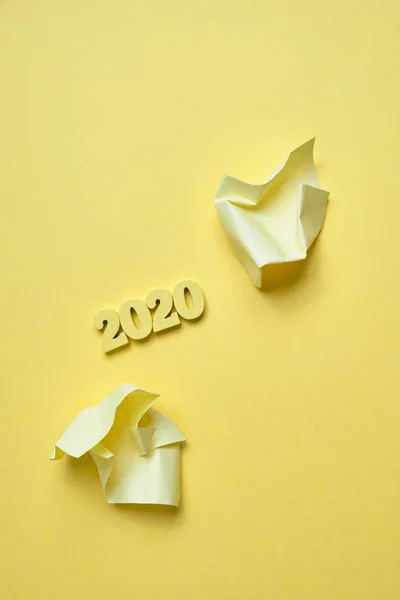 Stickers froissés à côté de figurines en bois 2020 sur fond jaune. Vue de dessus. Vertical . — Photo