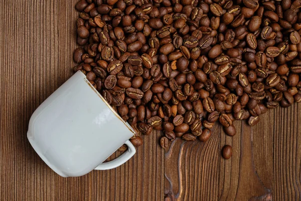 Un jet abstrait de grains de café fabriqués à partir d'une tasse blanche sur un fond en bois. Vue du dessus . — Photo