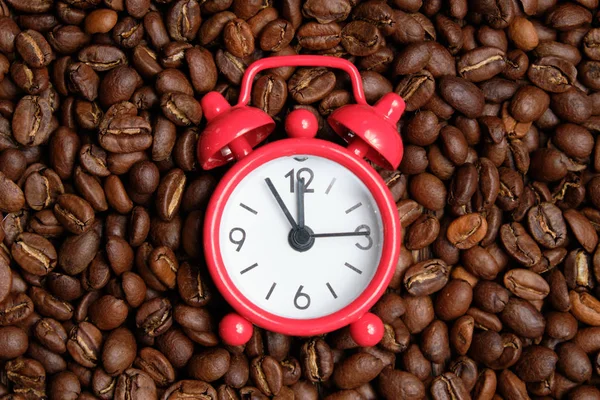 Rote Uhr auf dem Hintergrund von Kaffeebohnen. Konzept die nötige Zeit zum Braten. — Stockfoto