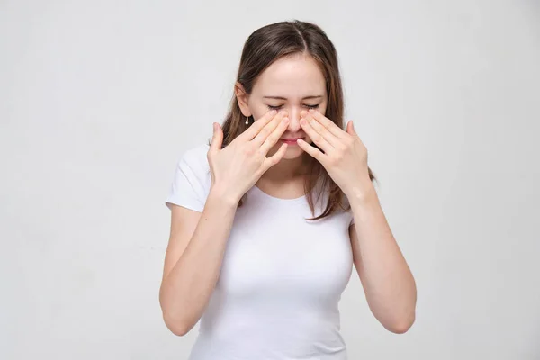 Ett porträtt av en ung flicka i vit skjorta hade en hand i pannan. Begreppet förkylningssjukdom vid hög temperatur, influensa. — Stockfoto