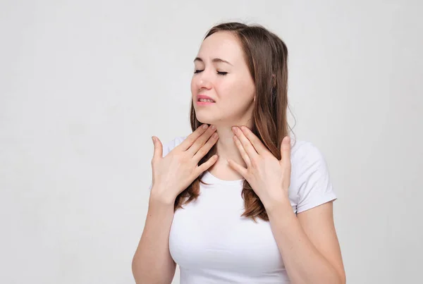 Charming girl in a white T-shirt on a gray background touches a — Stock Photo, Image