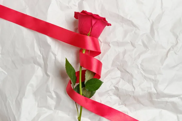 Hermosa rosa roja con cinta sobre papel arrugado . — Foto de Stock
