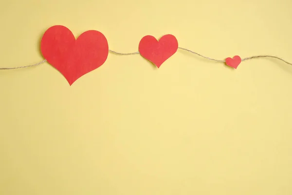 Koord van garen met rode harten op een gele achtergrond. Bovenaanzicht. — Stockfoto