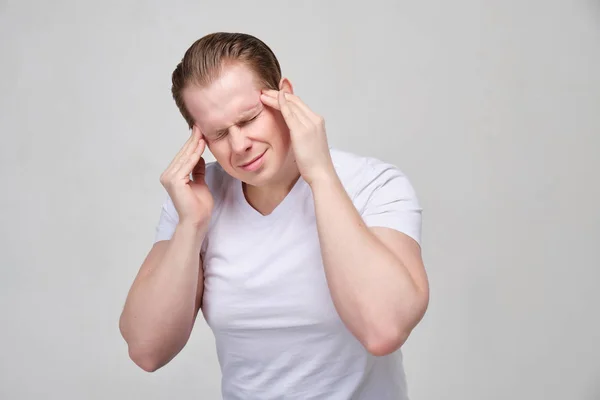 Um homem de camisa branca massaja a cabeça. O conceito de dor de cabeça, enxaqueca . — Fotografia de Stock