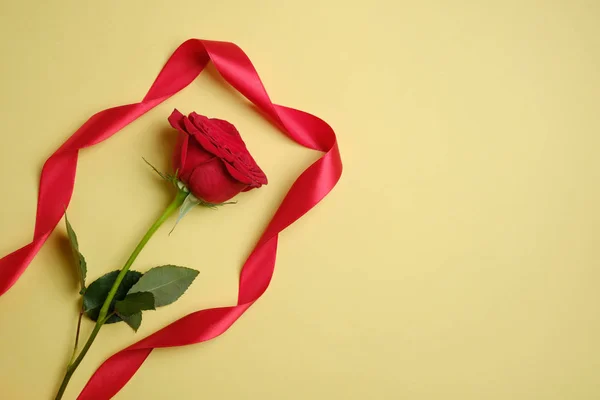 Rosa roja con una cinta sobre un fondo amarillo. espacio de copia . — Foto de Stock