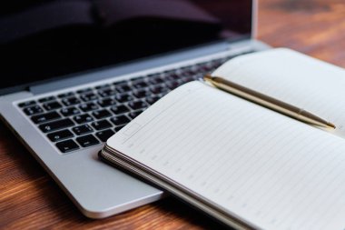 Diary on a laptop on a white wooden background. The concept of new tasks for the day.
