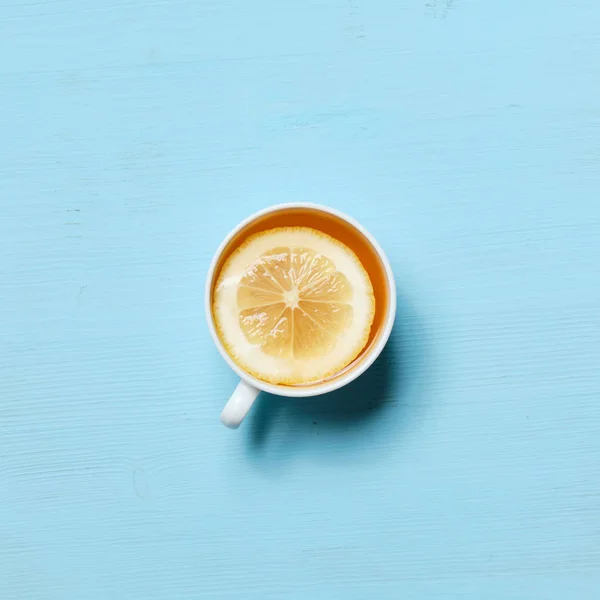 Secangkir teh hitam dengan irisan lemon dengan latar belakang biru pucat . — Stok Foto