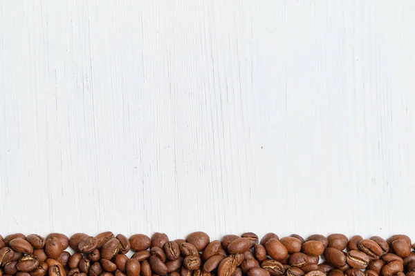 Granos de café asados sobre un fondo de madera blanca. Copiar espacio . — Foto de Stock