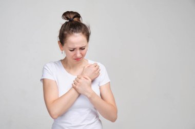 Girl in a white T-shirt massages a brush. Concept of joint pain.