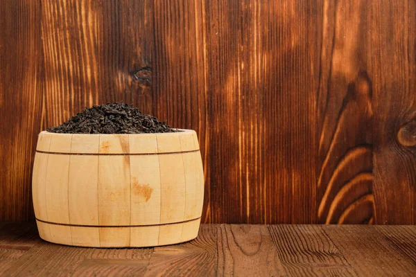 Chá preto em um barril contra o fundo de um fundo de madeira queimada. Espaço de cópia . — Fotografia de Stock