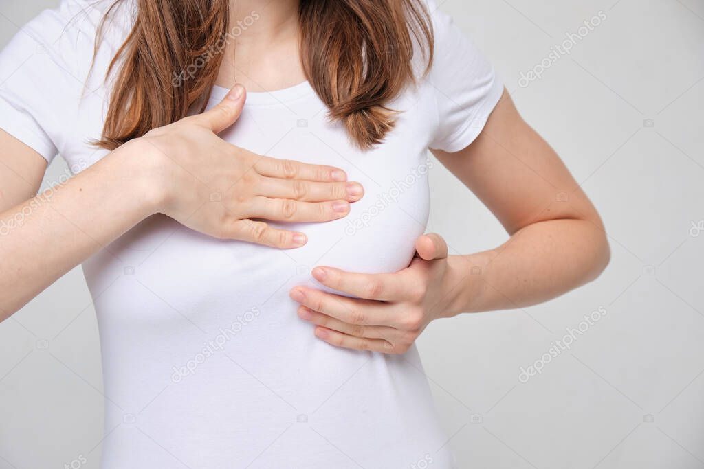 The girl is massaging her breasts. Disease or cancer screening concept.