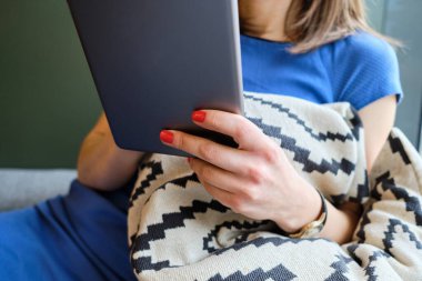 The girl sits in a cafe and works on a tablet.