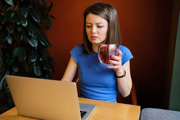 Το κορίτσι κάθεται στο καφέ και εργάζεται σε φορητό υπολογιστή και πίνει τσάι. — Φωτογραφία Αρχείου