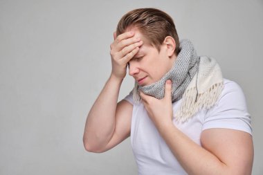 A man in a white T-shirt and scarf holds on to the throat and forehead of his head. The concept of labeled immunity and the body.