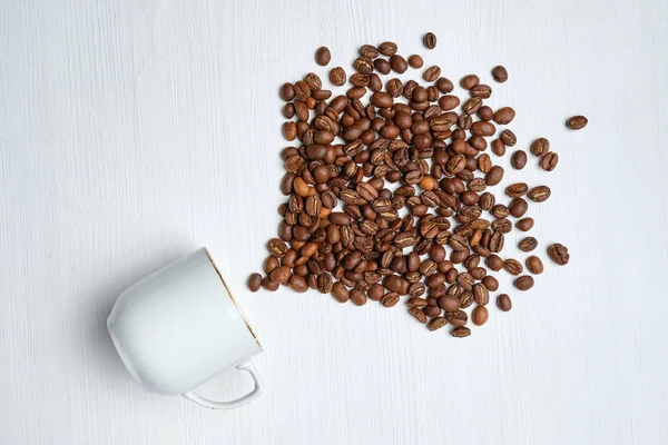 Una fuente abstracta de granos de café hechos de una taza blanca sobre un fondo de madera . — Foto de Stock