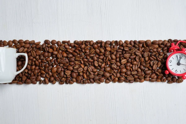 Le concept Abrakt est le moment de la préparation du café. grains de café avec une horloge rouge et une tasse blanche sur un fond en bois. Vue du dessus . — Photo