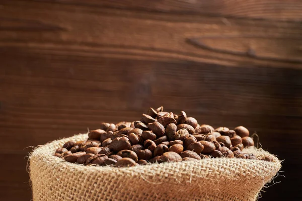 Knitted bag with coffee beans against the background of a adored wooden background. Copy space.