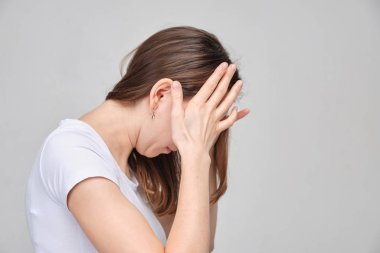 A girl in a white T-shirt massages her head from fatigue. Bad sleep concept.